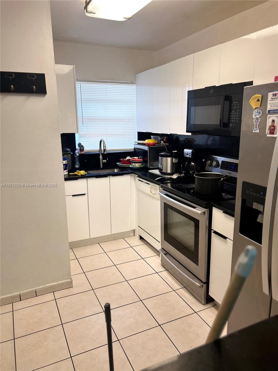 1630 West 46th Street, Unit 511C Hialeah, FL 33012 - Photo 6 of 12 a kitchen with granite countertop a sink and a stove top oven