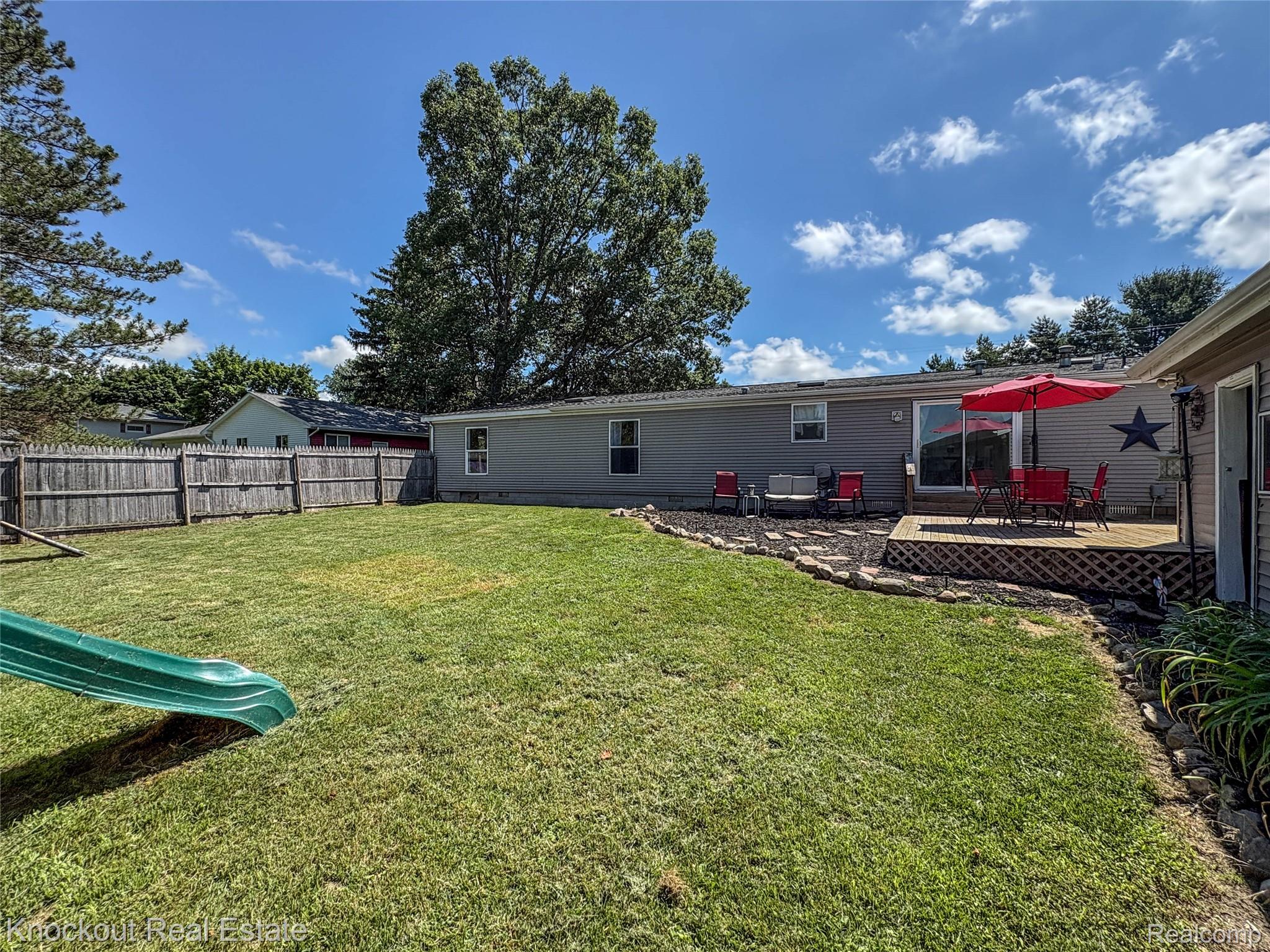 7760 Bell Road Birch Run, MI 48415 - Photo 56 of 68 Spacious backyard featuring a wooden privacy fence, a well-maintained lawn, and a multi-level wooden deck with lattice skirting