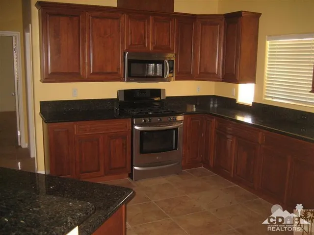 a kitchen with granite countertop wood cabinets and stainless steel appliances