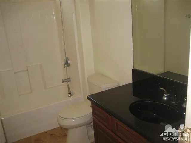 a bathroom with a granite countertop toilet and sink