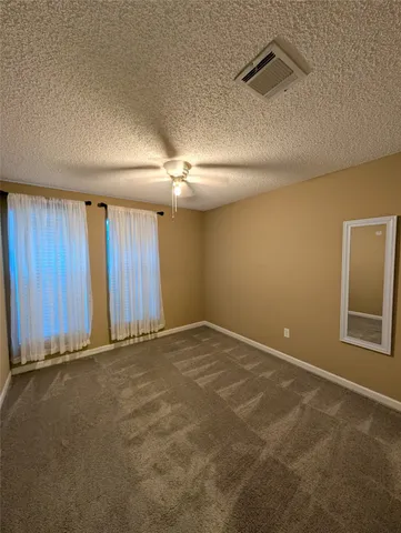 an empty room with windows and fan