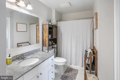 a bathroom with a granite countertop sink toilet and shower