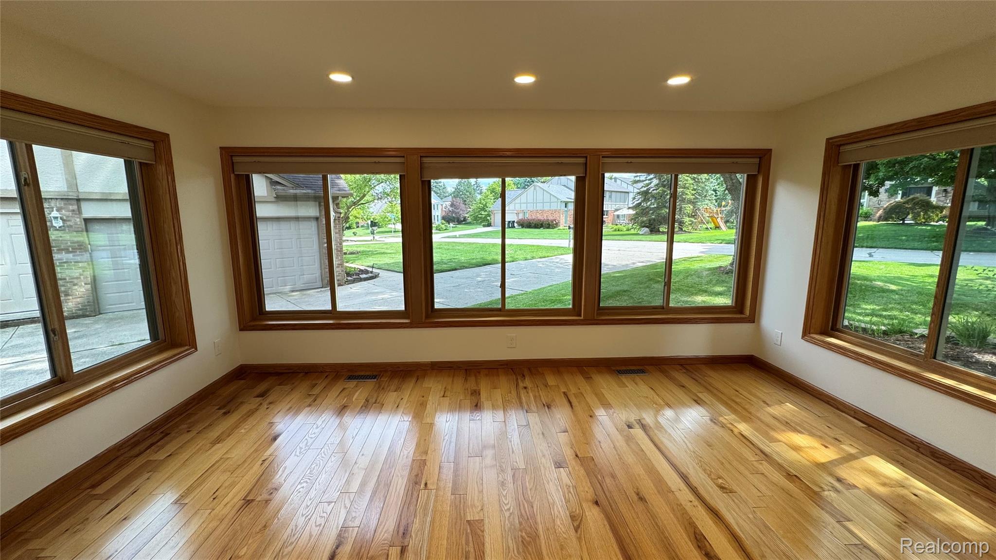 3440 Salem Drive Rochester, MI 48306 - Photo 6 of 33 Hardwood flooring in a room with five large windows featuring wood-finish trim