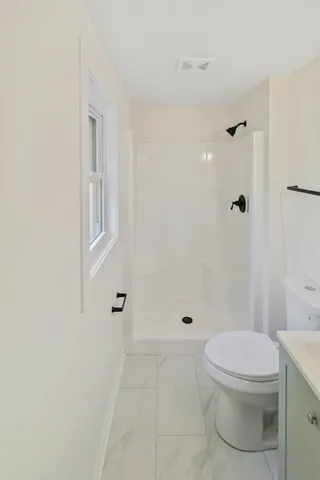 a bathroom with a toilet a sink a shower and a mirror