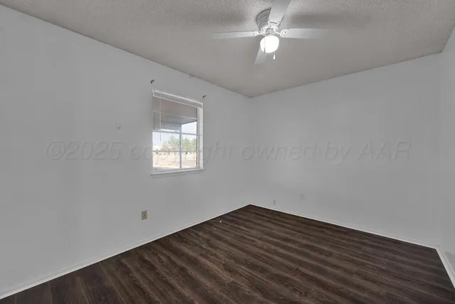 an empty room with ceiling fan and window