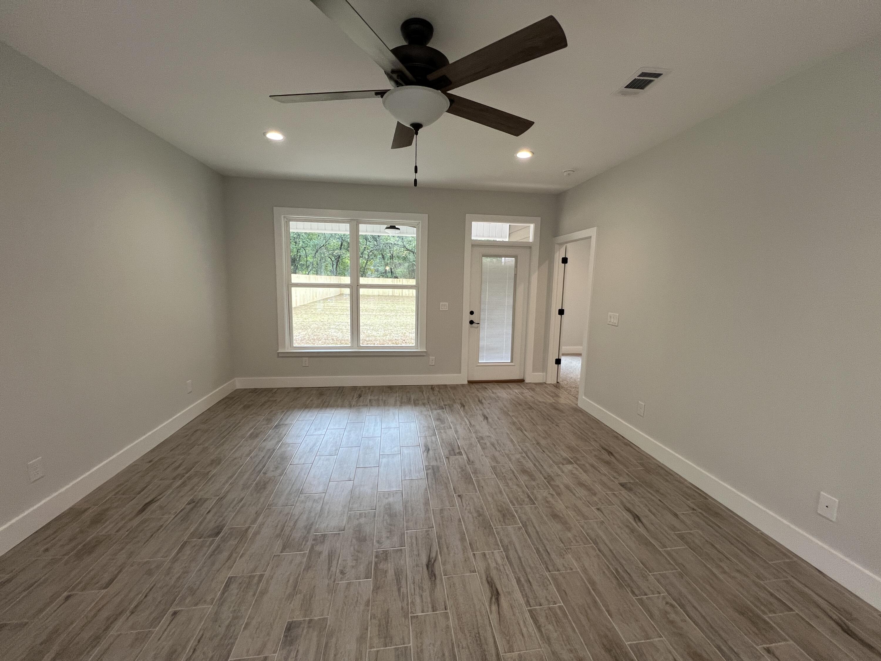 1491 Cat-Mar Road Niceville, FL 32578 - Photo 12 of 30 an empty room with wooden floor ceiling fan and windows