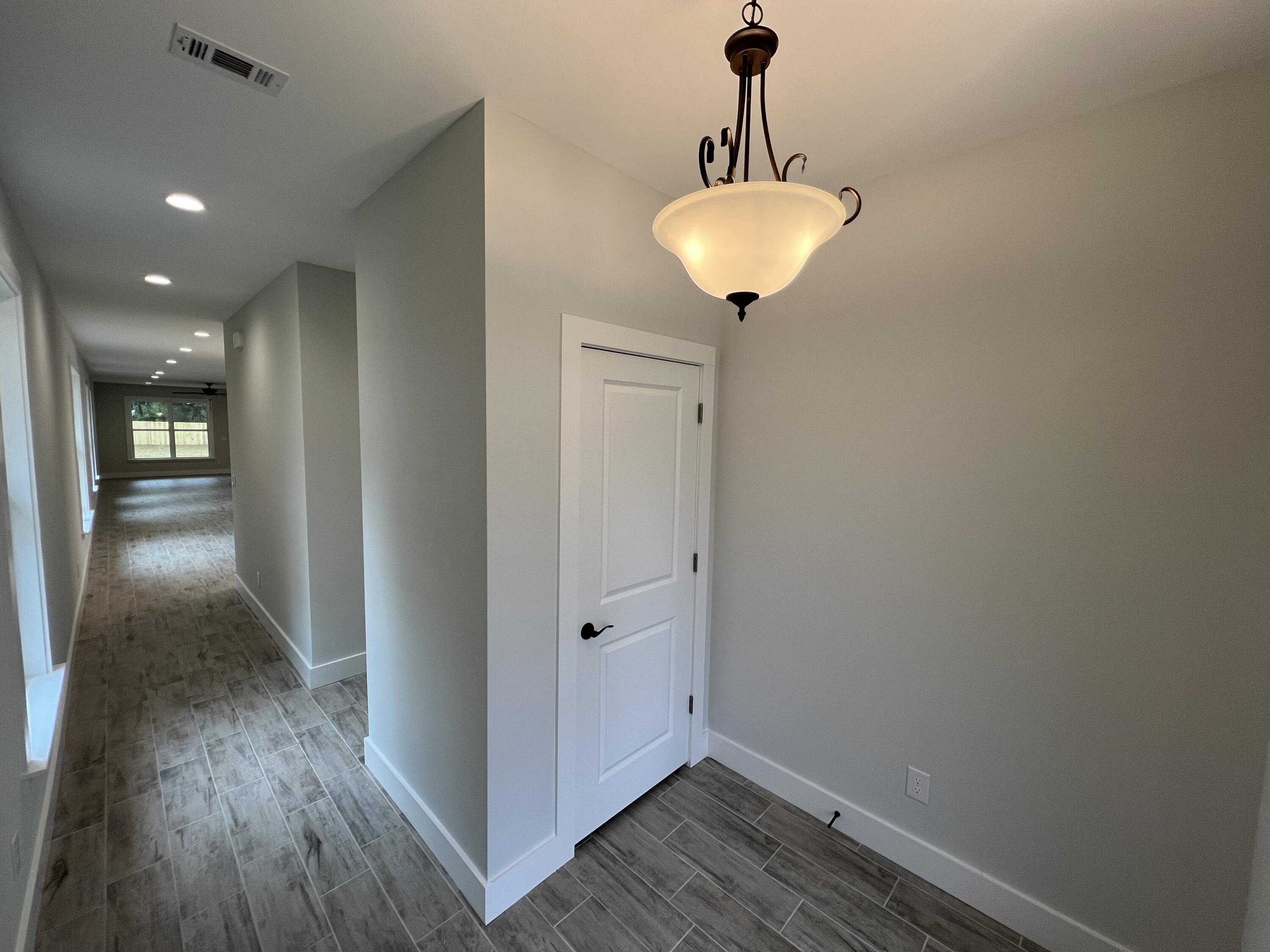 1491 Cat-Mar Road Niceville, FL 32578 - Photo 2 of 30 a view of a hallway with wooden floor and a chandelier