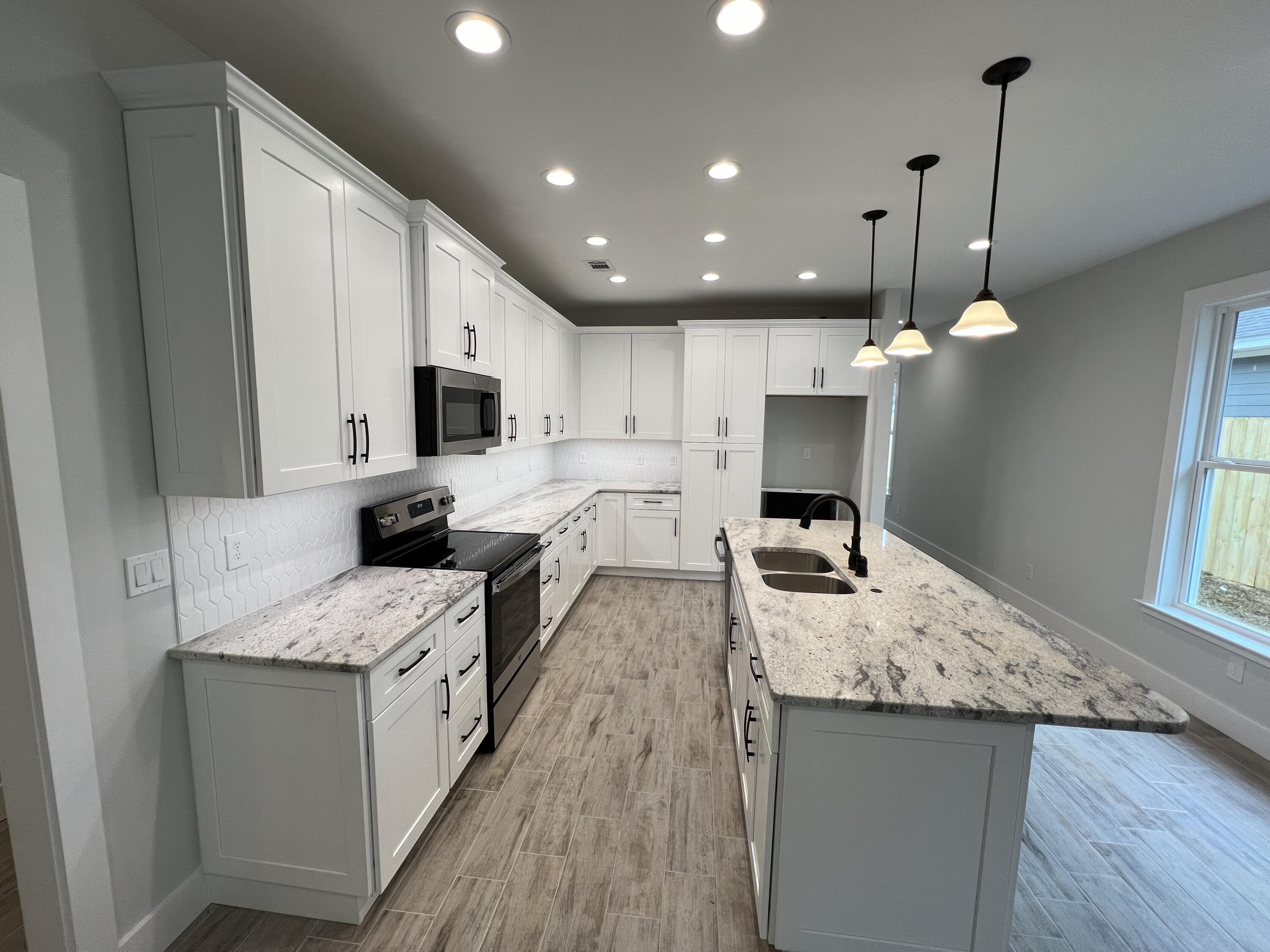 1491 Cat-Mar Road Niceville, FL 32578 - Photo 6 of 30 a large kitchen with kitchen island a stove a sink a center island and wooden floor