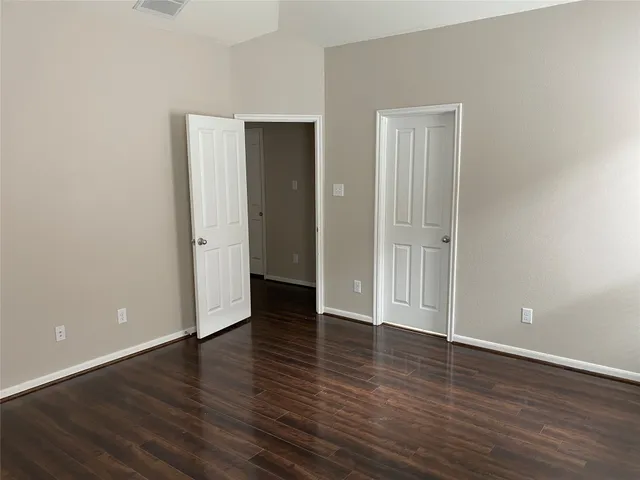 a view of an empty room with wooden floor and closet