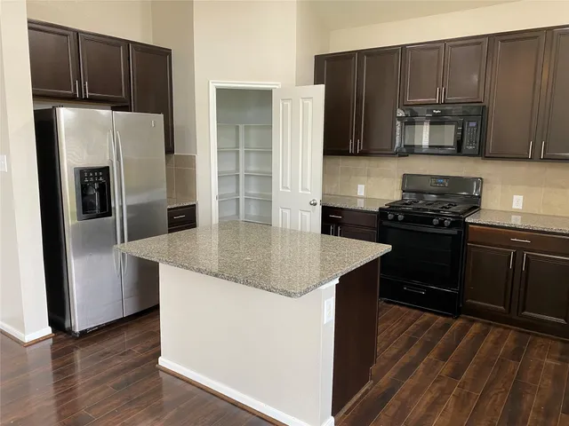 a kitchen with wooden cabinets a refrigerator and a stove top oven