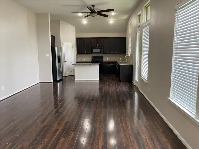 a kitchen with kitchen island wooden floors appliances and cabinets