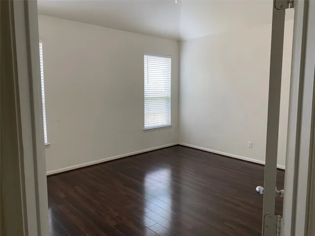 an empty room with wooden floor and window