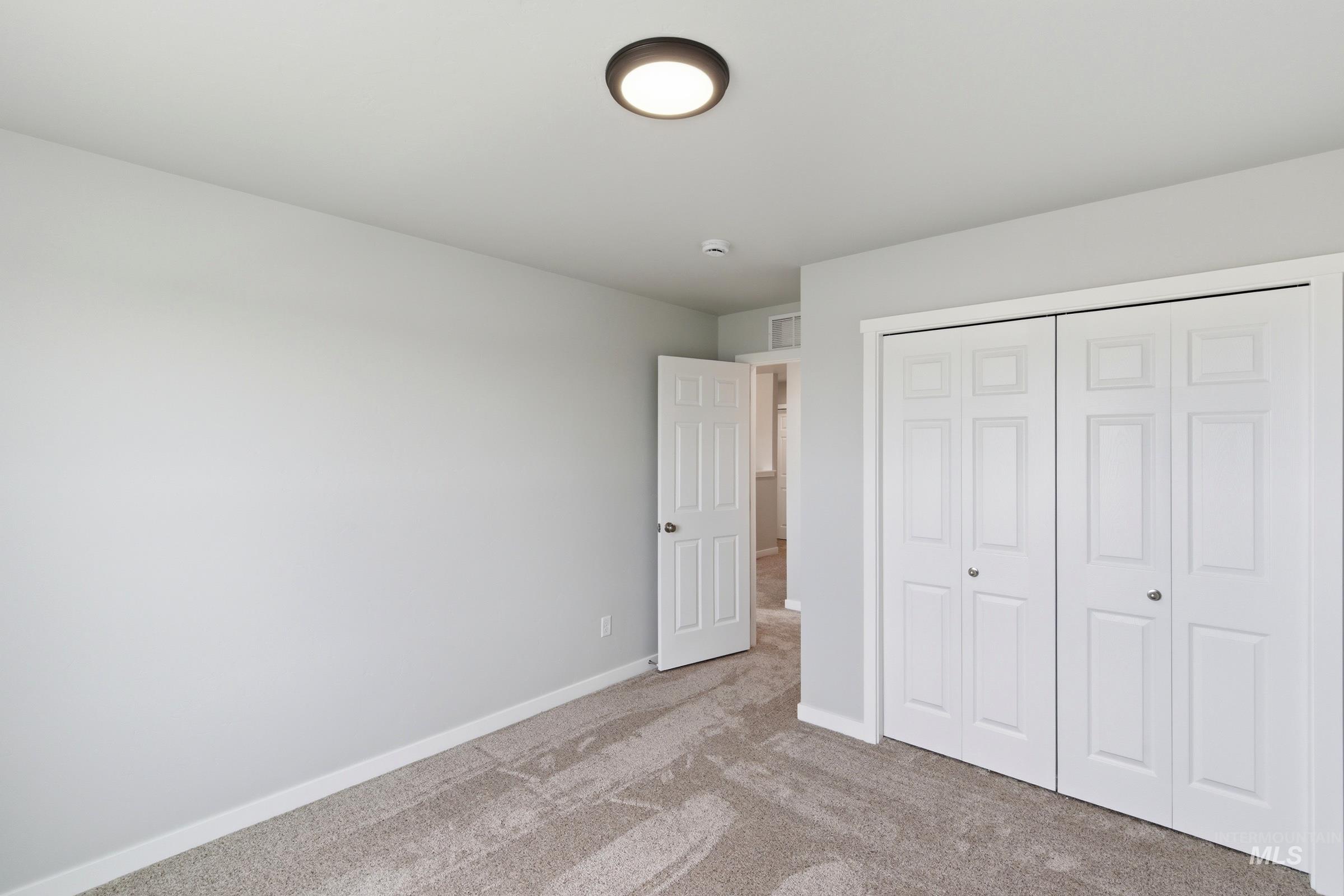 16558 Dunning Way Caldwell, ID 83607 - Photo 21 of 35 Neutral wall tones with a ceiling-mounted light fixture, white bi-fold closet doors, and carpet flooring