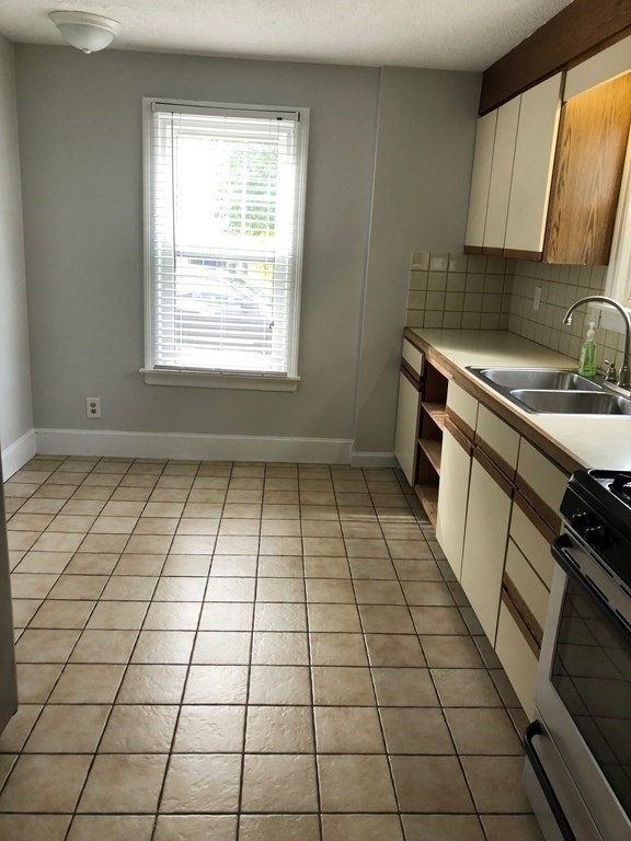 410 Plumtree Road Springfield, MA 01118 - Photo 8 of 31 a kitchen with a sink a stove a window and cabinets