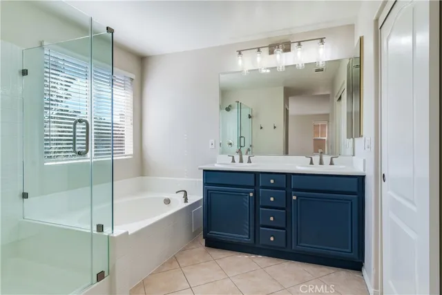 a bathroom with a tub a double vanity sink and mirror