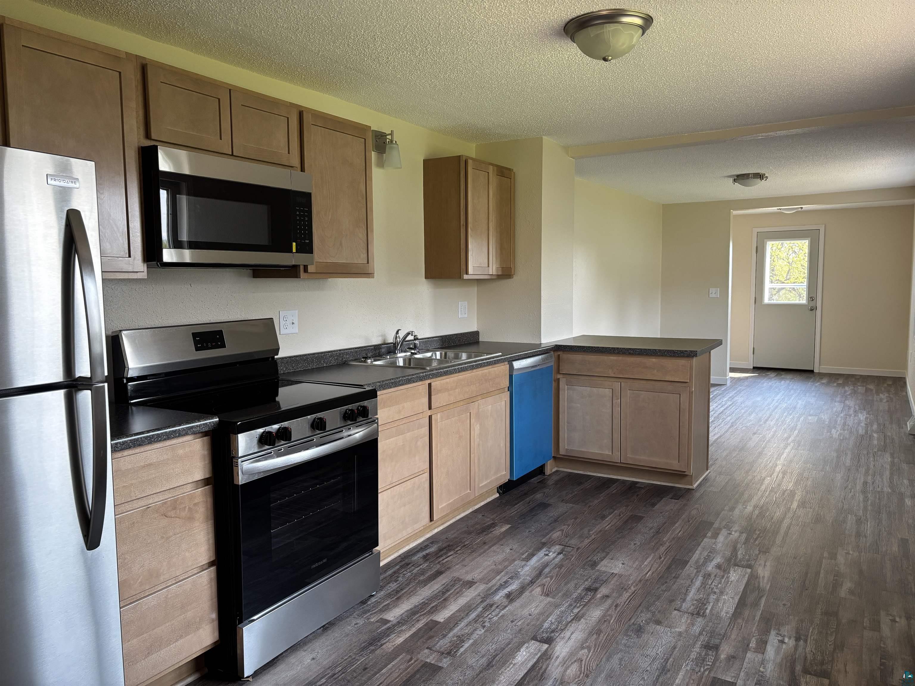 408 Midway Avenue Proctor, MN 55810 - Photo 12 of 20 Kitchen featuring stainless steel appliances, a sink, dark countertops, dark wood-style floors, and a textured ceiling