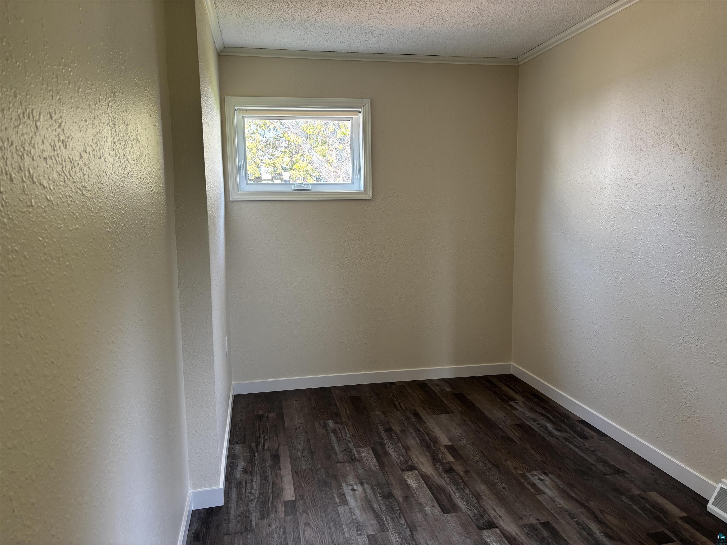 408 Midway Avenue Proctor, MN 55810 - Photo 16 of 20 Spare room featuring ornamental molding, dark wood-type flooring, a textured ceiling, baseboards, and a textured wall