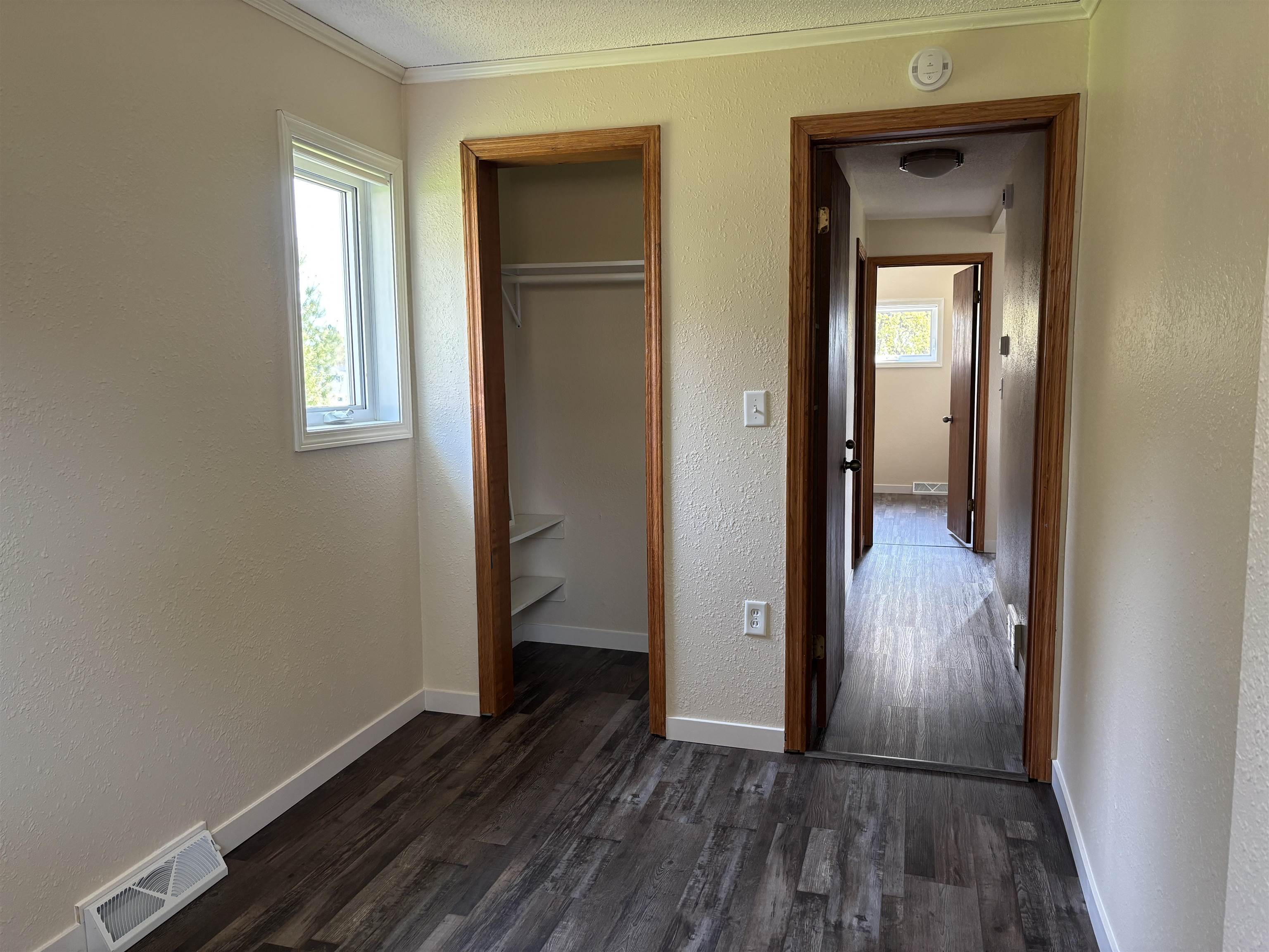 408 Midway Avenue Proctor, MN 55810 - Photo 17 of 20 Unfurnished bedroom featuring dark wood-style floors, crown molding, a closet, baseboards, and a textured wall