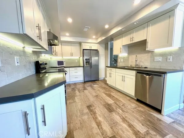 a large kitchen with stainless steel appliances kitchen island granite countertop a sink and cabinets