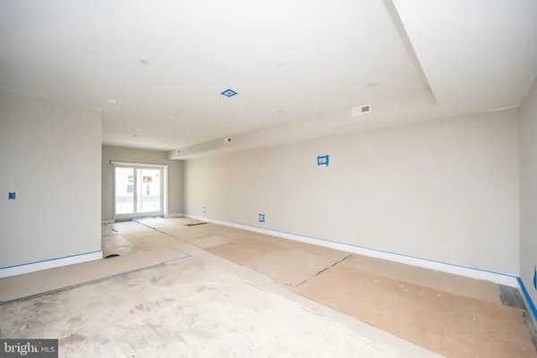 a view of a hallway to an empty room with wooden floor and a window