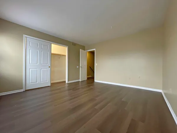 a view of an empty room with wooden floor and closet