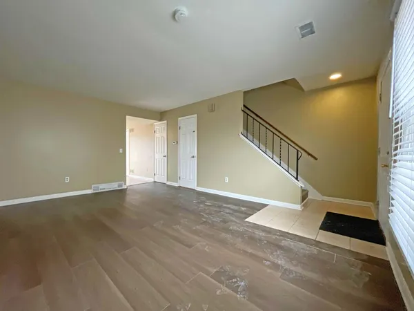 a view of an empty room with wooden floor and stairs