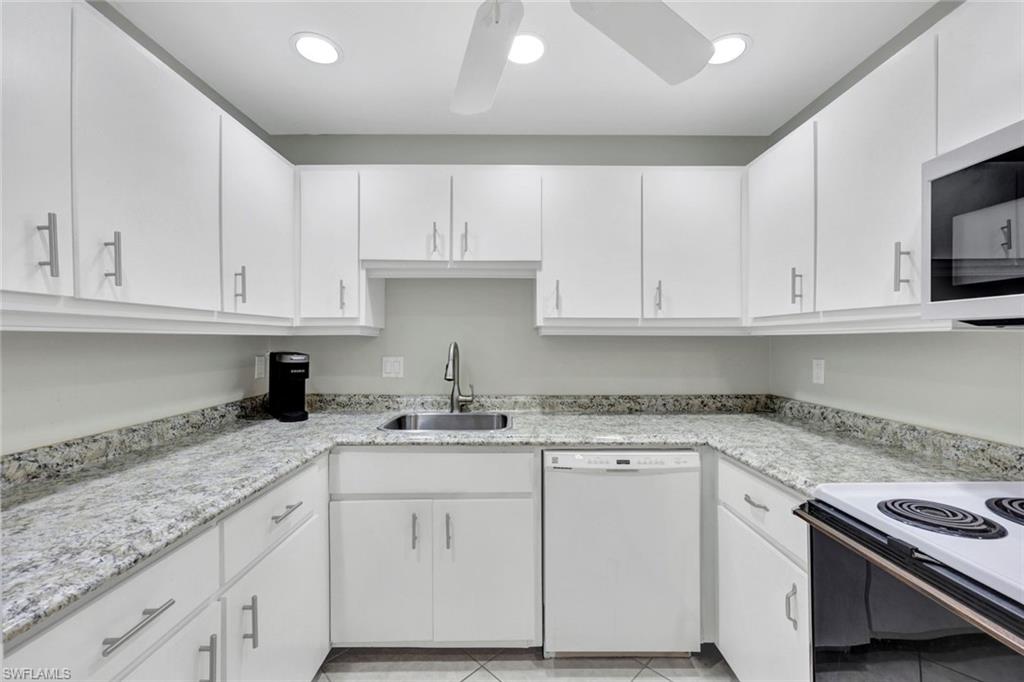 509 Roma Court, Unit 202 Naples, FL 34110 - Photo 3 of 18 Kitchen with white appliances, white cabinets, light tile patterned floors, and recessed lighting