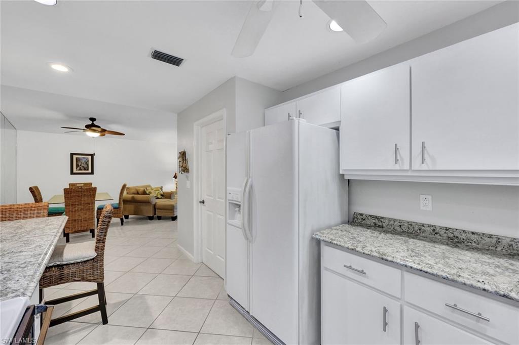 509 Roma Court, Unit 202 Naples, FL 34110 - Photo 5 of 18 Kitchen featuring a ceiling fan, light stone countertops, white refrigerator with ice dispenser, white cabinets, and recessed lighting
