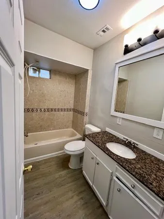 a bathroom with a granite countertop toilet sink and mirror