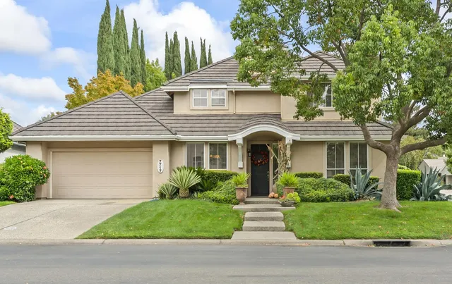 a front view of a house with plants and garden