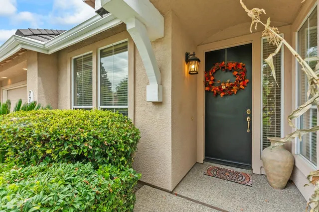 a view of a white house next to a yard with plants and trees
