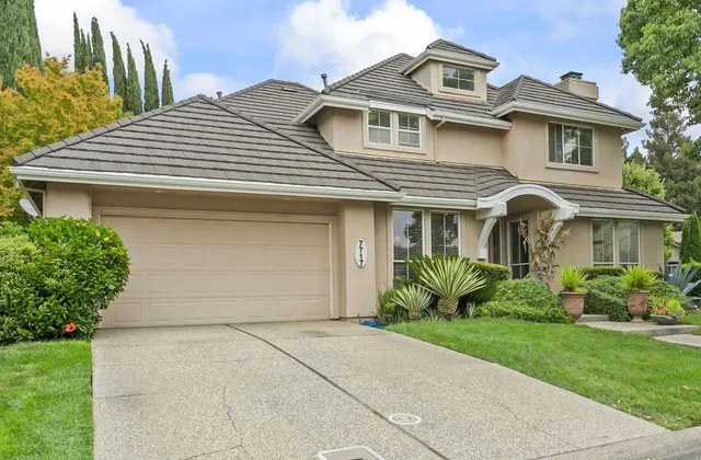 a front view of a white house with a yard and plants