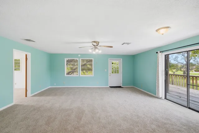 an empty room with windows and ceiling fan