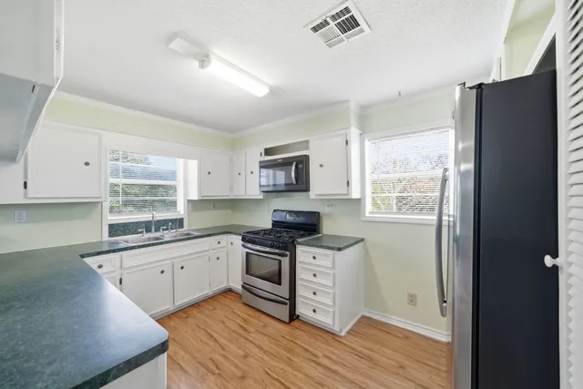 a kitchen with granite countertop a stove top oven a sink dishwasher and a refrigerator with wooden floor