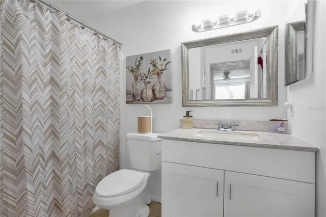 a bathroom with a toilet sink vanity and mirror