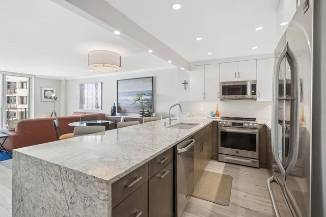 a large kitchen with stainless steel appliances granite countertop a sink a stove and a refrigerator