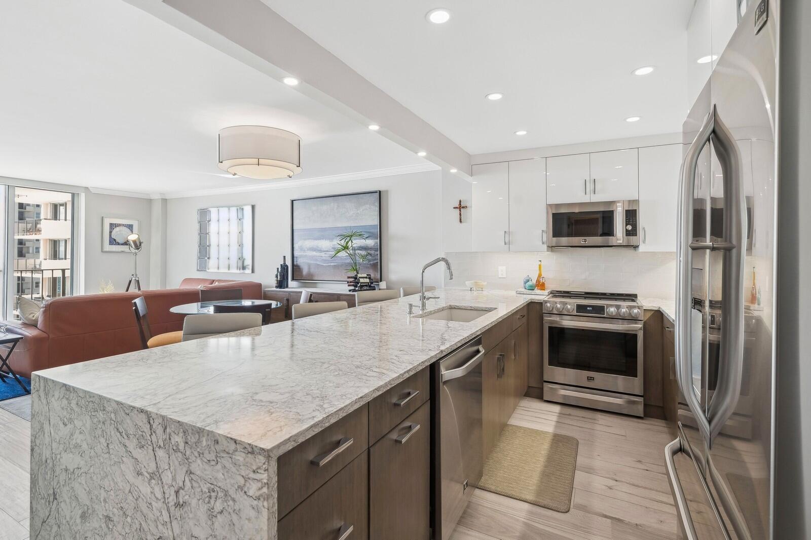 1900 South Ocean Boulevard, Unit 11B Lauderdale-by-the-Sea, FL 33062 - Photo 1 of 19 a large kitchen with stainless steel appliances granite countertop a sink a stove and a refrigerator