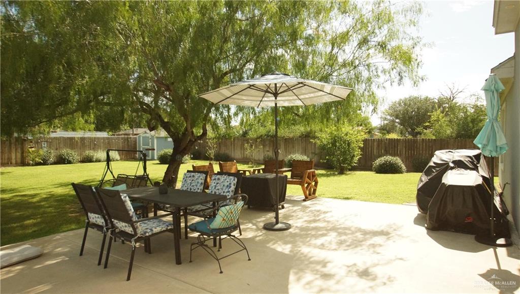 414 Ric Mar Street Edinburg, TX 78541 - Photo 4 of 36 Expansive concrete patio with a large shade tree, a manicured lawn, and a privacy fence