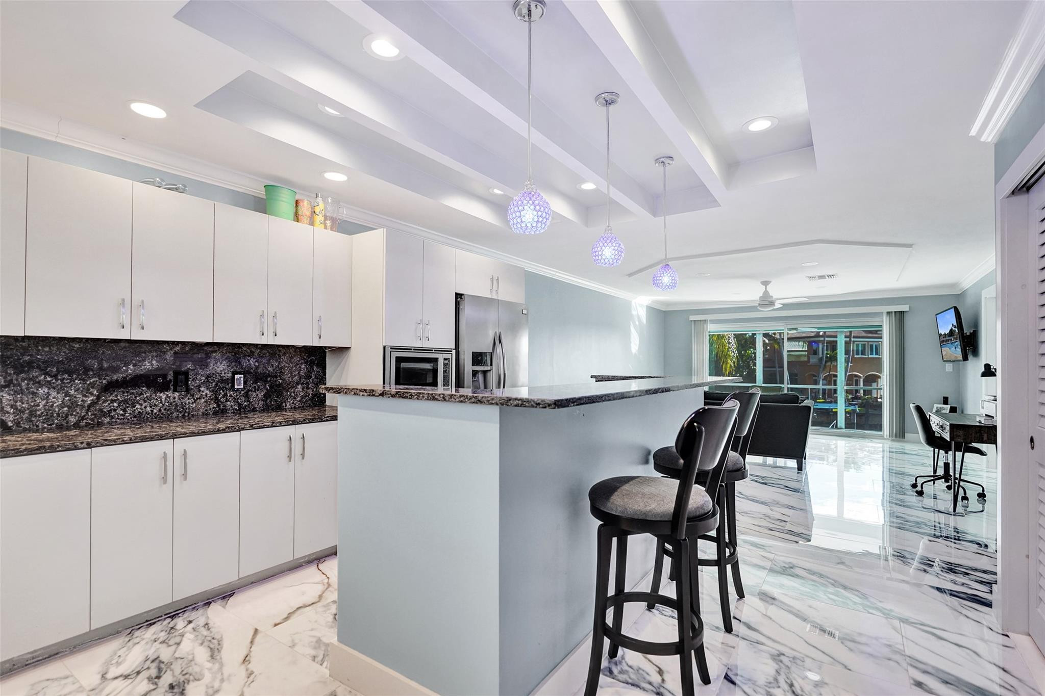 2330 Northeast 36th Street, Unit 9 Lighthouse Point, FL 33064 - Photo 12 of 48 a kitchen with stainless steel appliances kitchen island granite countertop a table chairs in it and wooden floors
