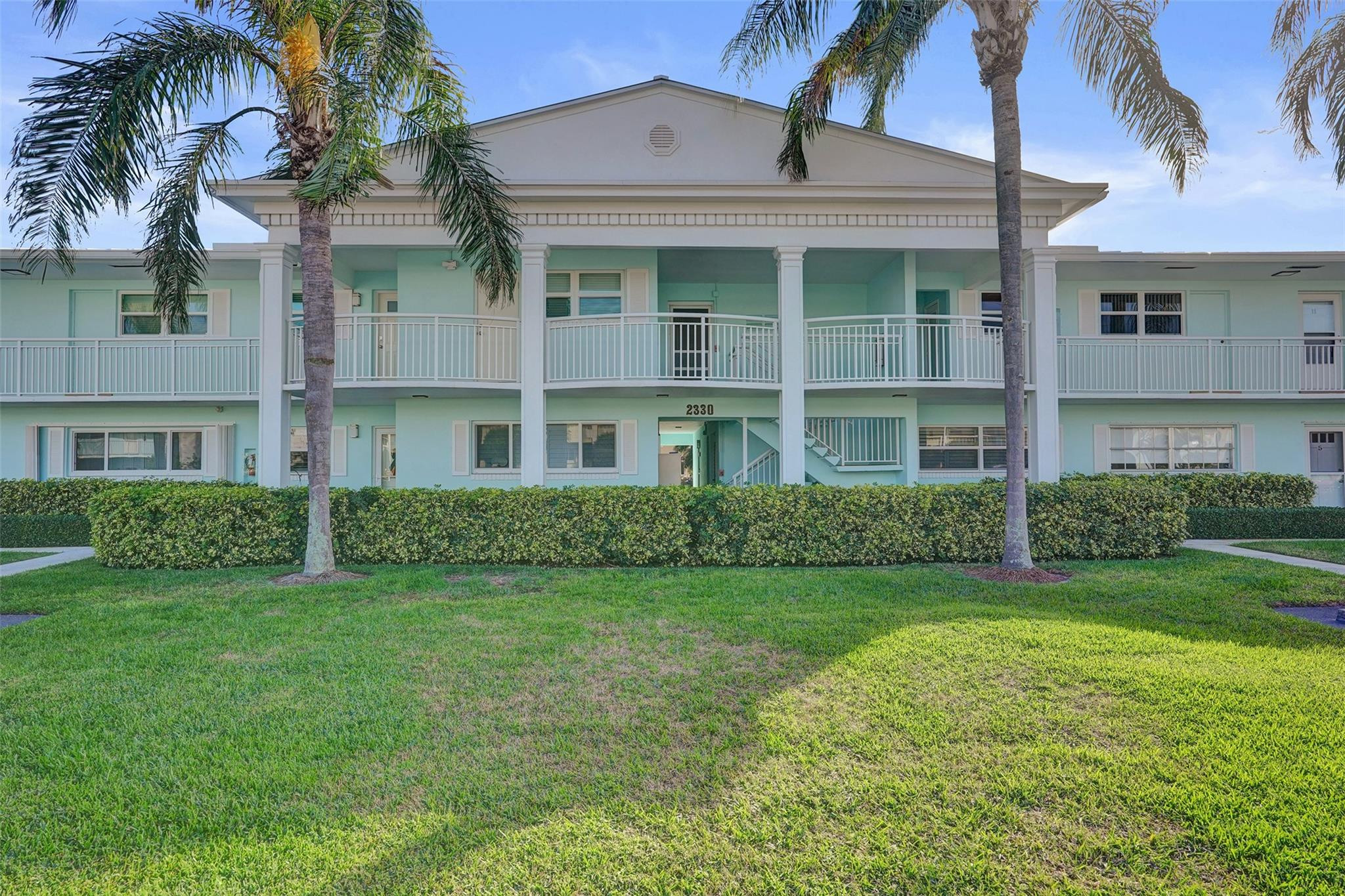 2330 Northeast 36th Street, Unit 9 Lighthouse Point, FL 33064 - Photo 6 of 48 a view of a brick building next to a yard with large trees