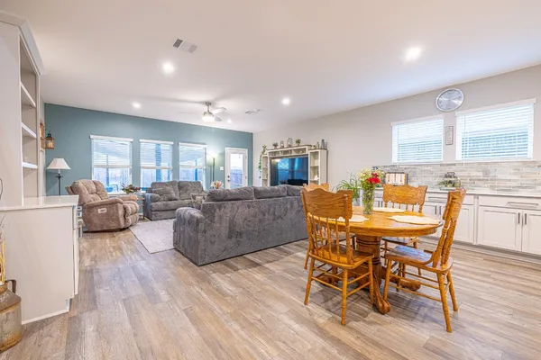 a living room with furniture wooden floor and a kitchen