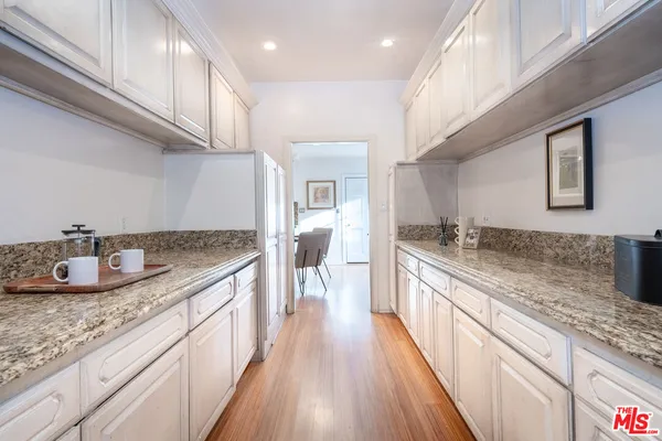 a large kitchen with granite countertop a large counter top a sink stainless steel appliances and cabinets