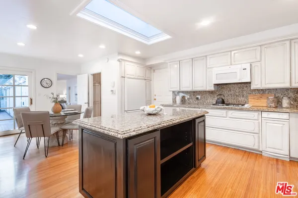 a kitchen with stainless steel appliances granite countertop a kitchen island hardwood floor sink stove dining table and chairs