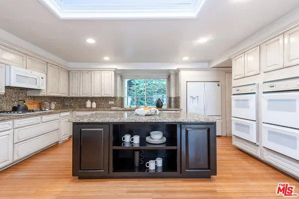 a kitchen with granite countertop a refrigerator and wooden cabinets