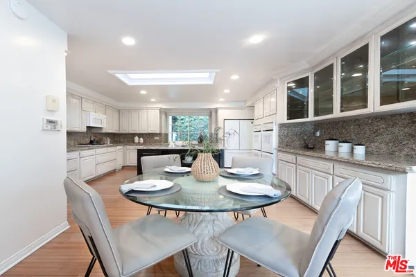 a kitchen with a dining table chairs and refrigerator