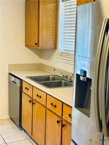 a view of a refrigerator a sink and cabinets