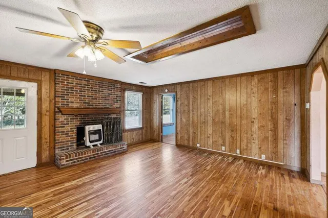 an empty room with wooden floor chandelier fan and windows