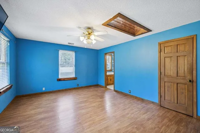 a view of empty room with wooden floor and fan