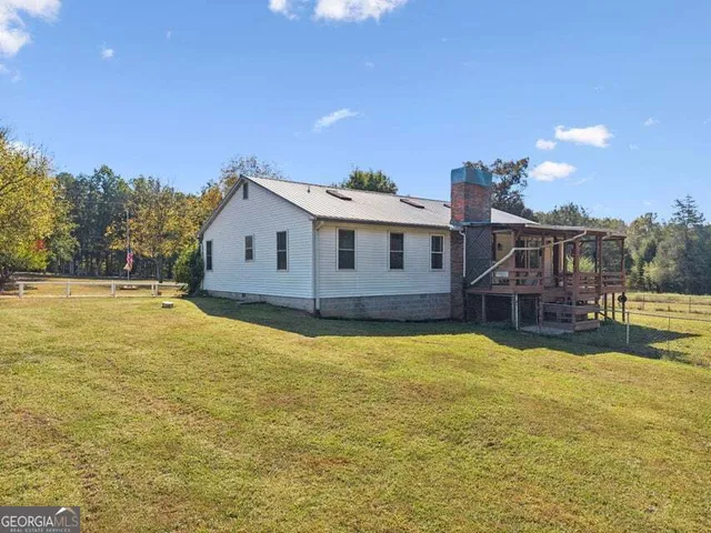 a front view of a house with yard and trees in the background