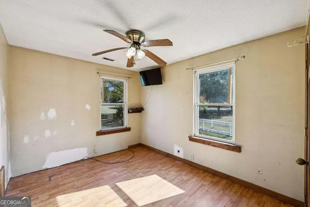 a view of an empty room with a window and wooden floor